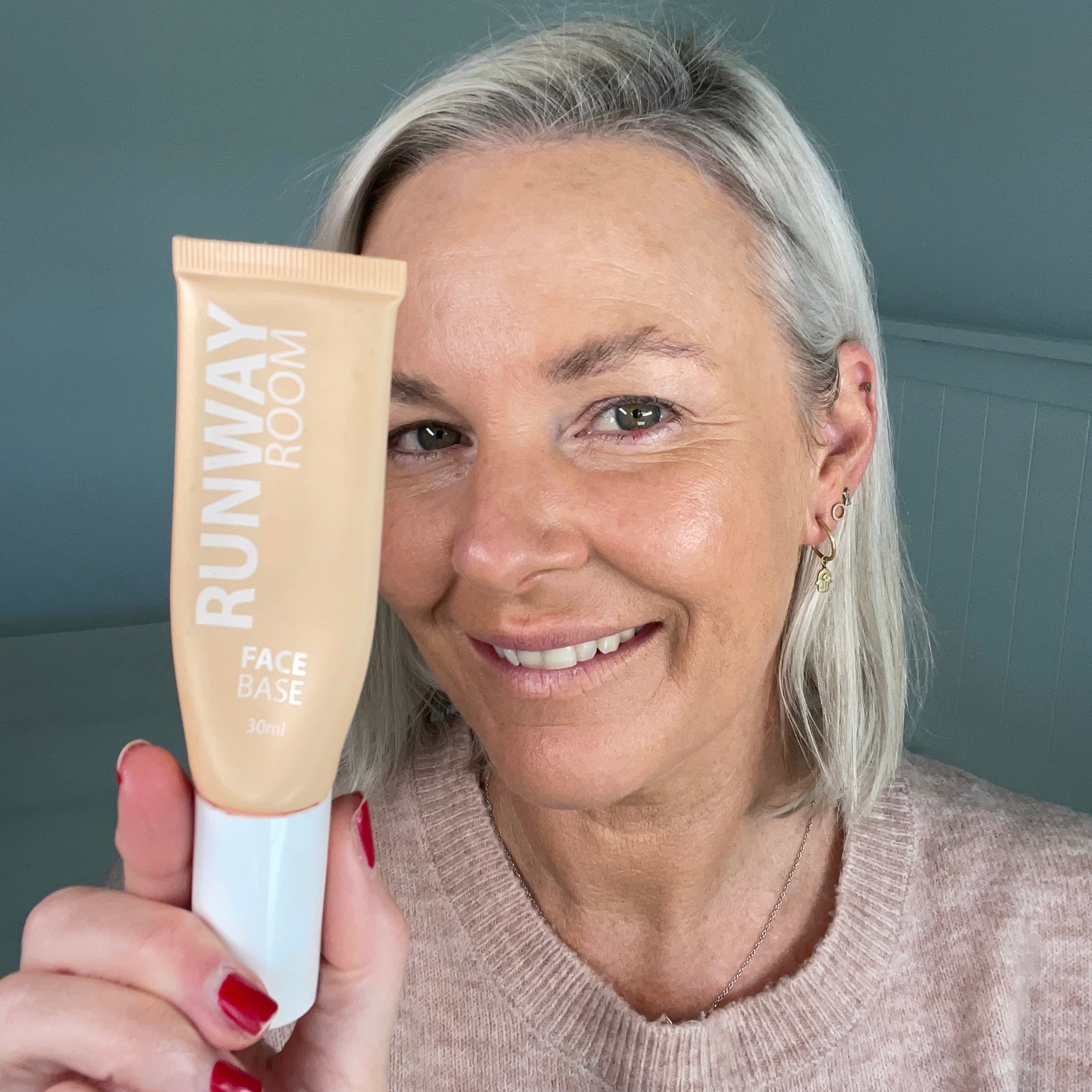 Woman holding a Runway Beauty product against a plain background